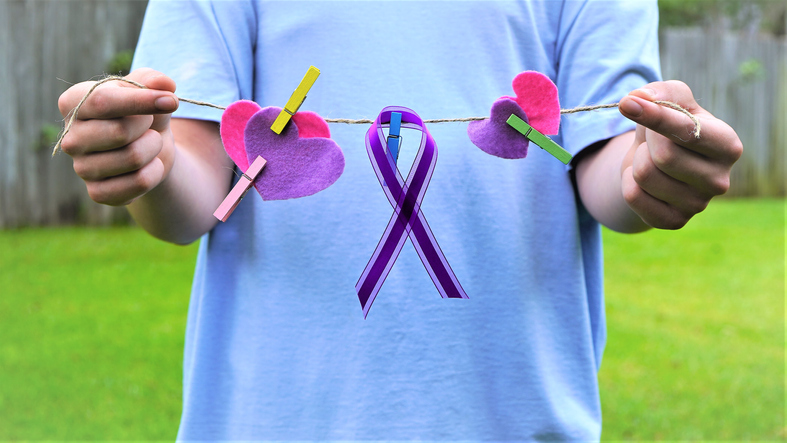 Child's hands holding a string of hearts and epilepsy ribbon