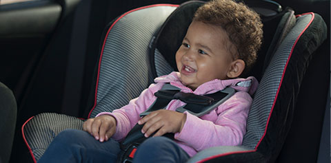 toddler girl safely buckled in car seat.