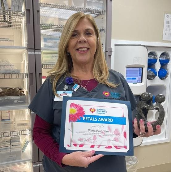 awardee wearing a headband of daisies, daisy award statue, and certificate.