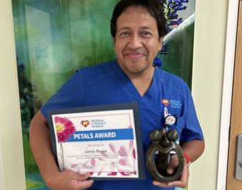 awardee wearing a headband of daisies, daisy award statue, and certificate.