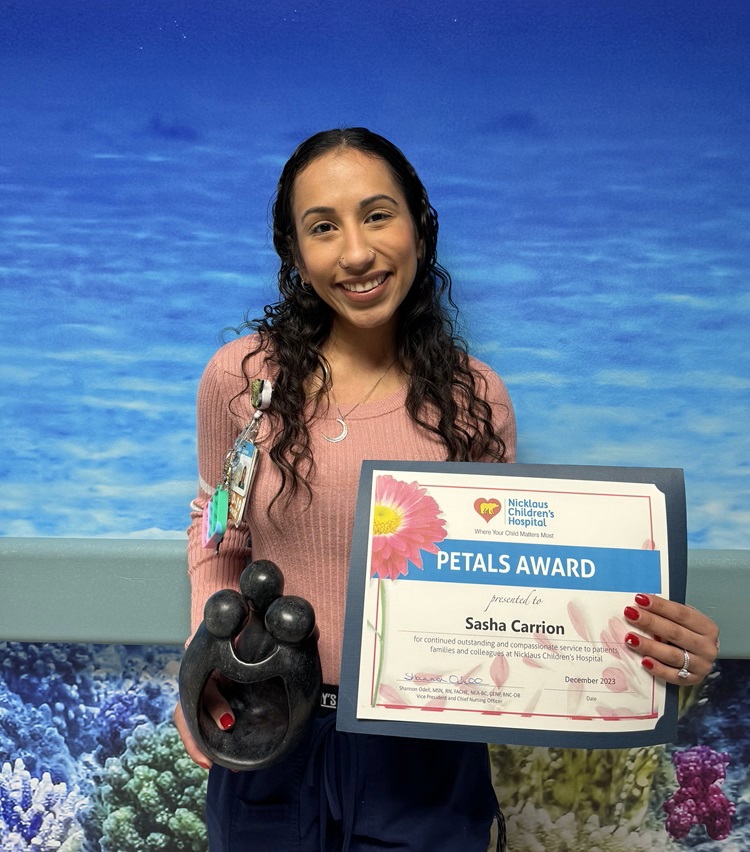 awardee wearing a headband of daisies, daisy award statue, and certificate.