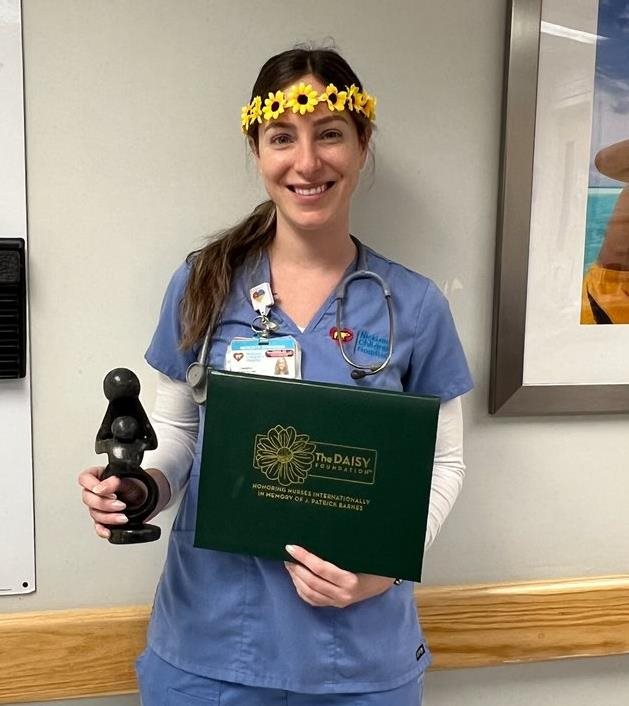 awardee wearing a headband of daisies, daisy award statue, and certificate.