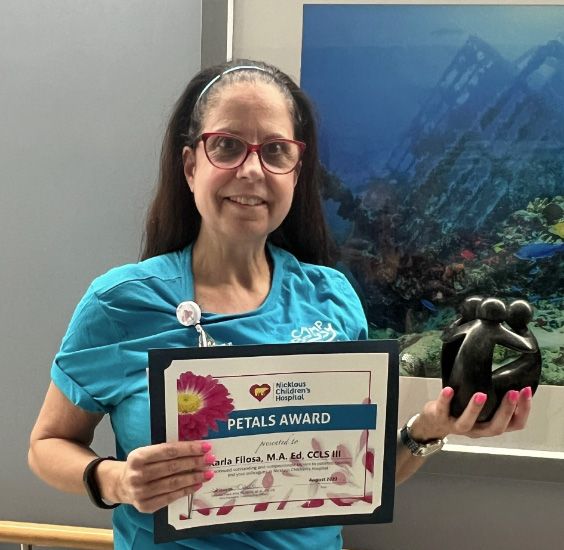 awardee wearing a headband of daisies, daisy award statue, and certificate.