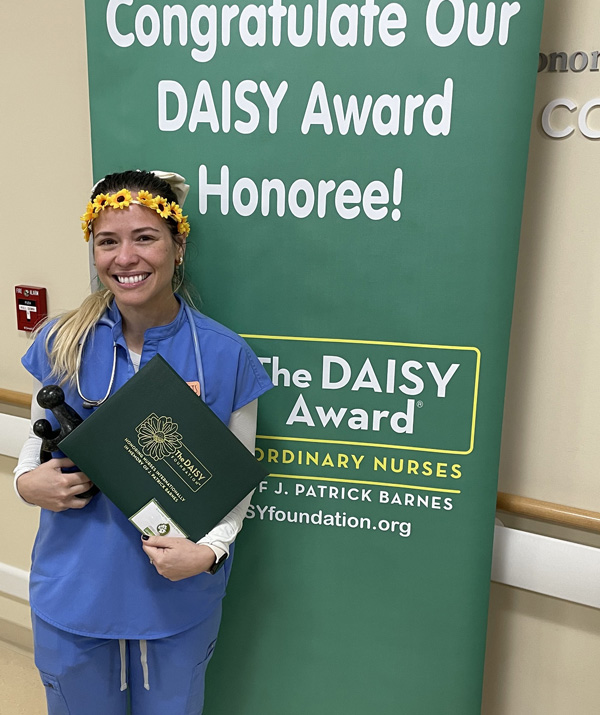 awardee wearing a headband of daisies, daisy award statue, and certificate.