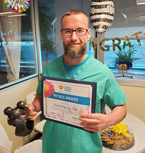awardee wearing a headband of daisies, daisy award statue, and certificate.