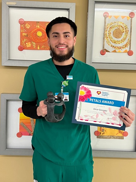 awardee wearing a headband of daisies, daisy award statue, and certificate.