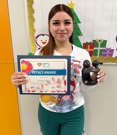awardee wearing a headband of daisies, daisy award statue, and certificate.