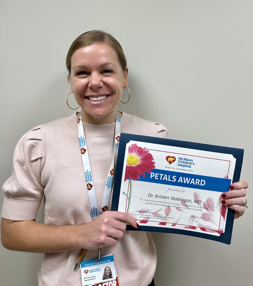 awardee wearing a headband of daisies, daisy award statue, and certificate.