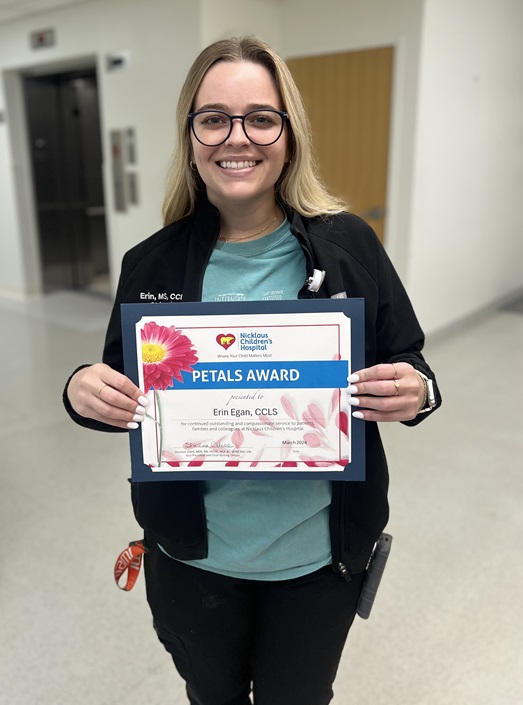 awardee wearing a headband of daisies, daisy award statue, and certificate.