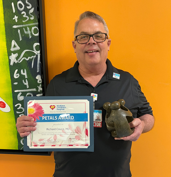 awardee wearing a headband of daisies, daisy award statue, and certificate.
