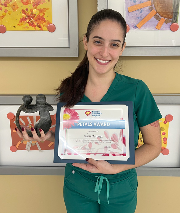 awardee wearing a headband of daisies, daisy award statue, and certificate.