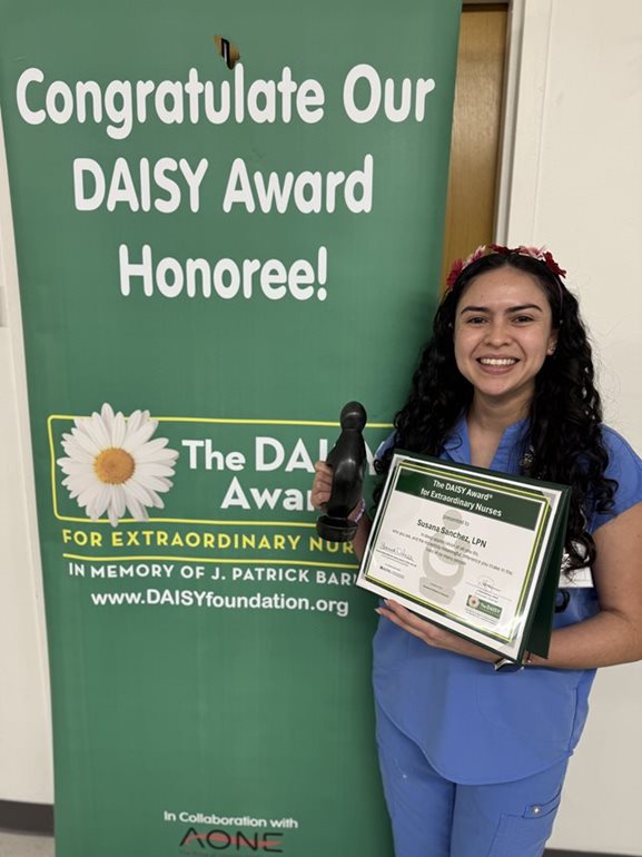 awardee wearing a headband of daisies, daisy award statue, and certificate.