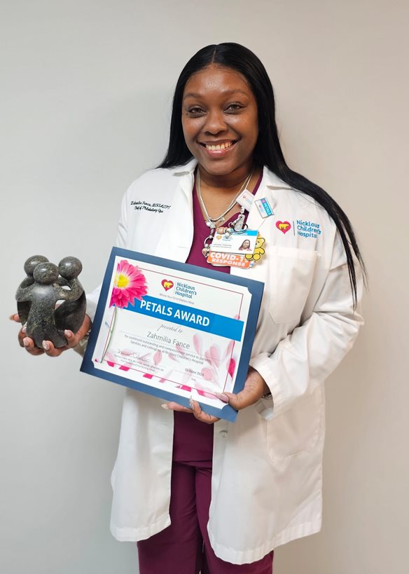 awardee wearing a headband of daisies, daisy award statue, and certificate.