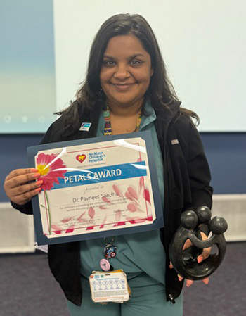 awardee wearing a headband of daisies, daisy award statue, and certificate.