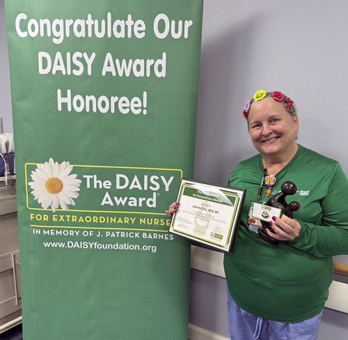 awardee wearing a headband of daisies, daisy award statue, and certificate.