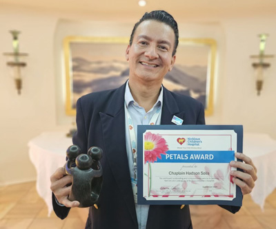 awardee wearing a headband of daisies, daisy award statue, and certificate.